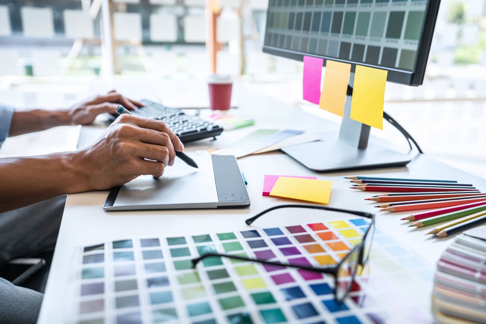 Designer working on brand identity with color swatches at a desk