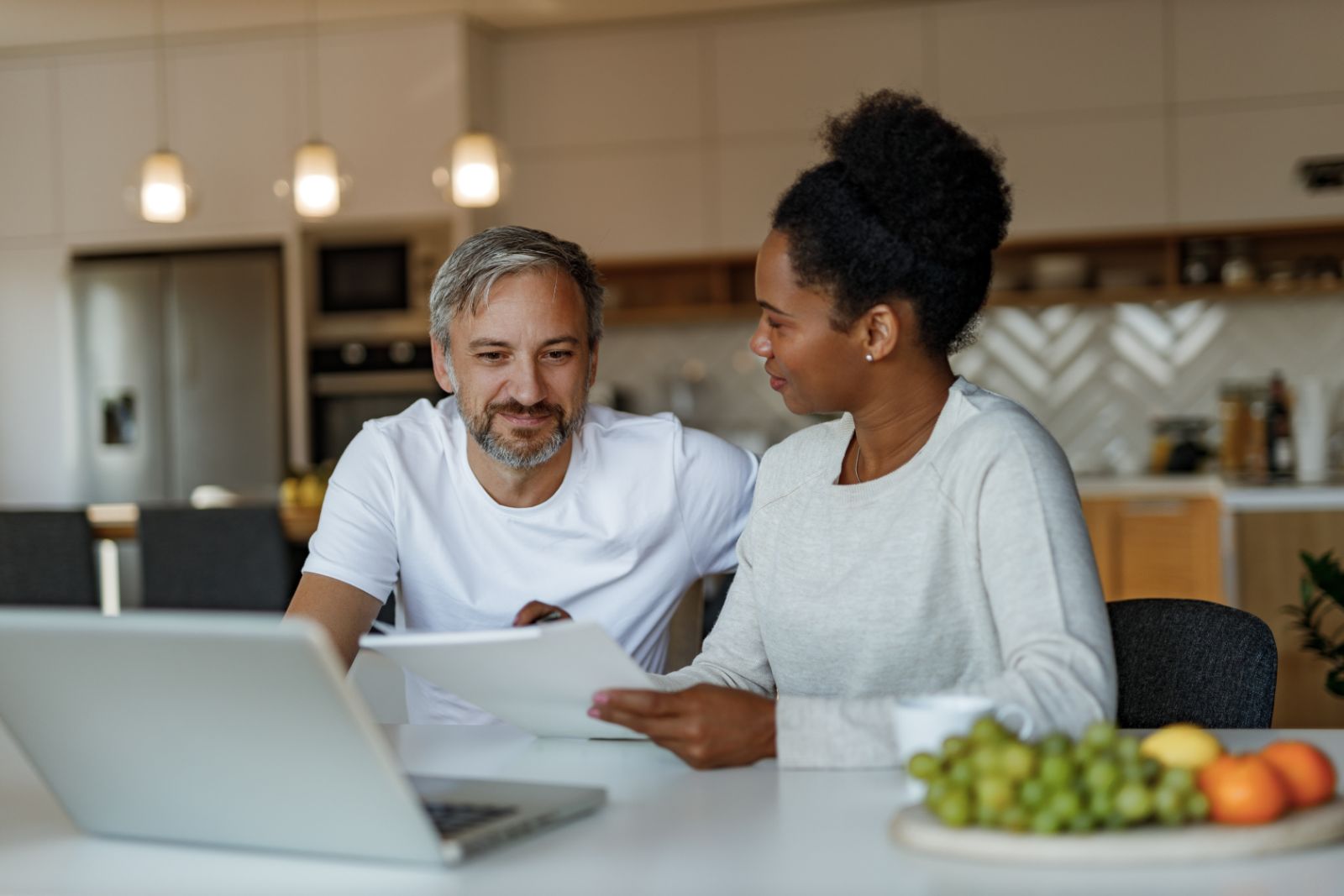 Couple reviewing documents and a laptop at the kitchen table